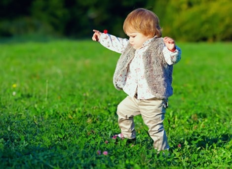 cute baby girl making first steps, colorful outdoors