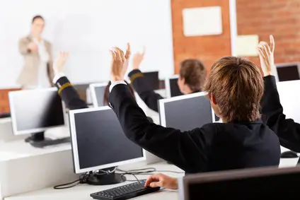 high school students hands up in computer class