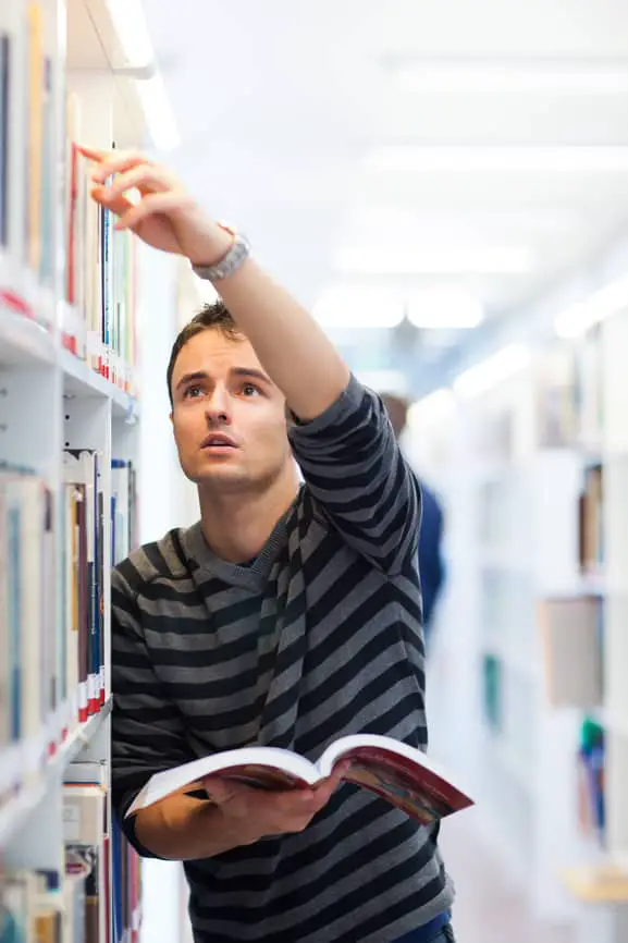 handsome young college student in a library (shallow DOF; color