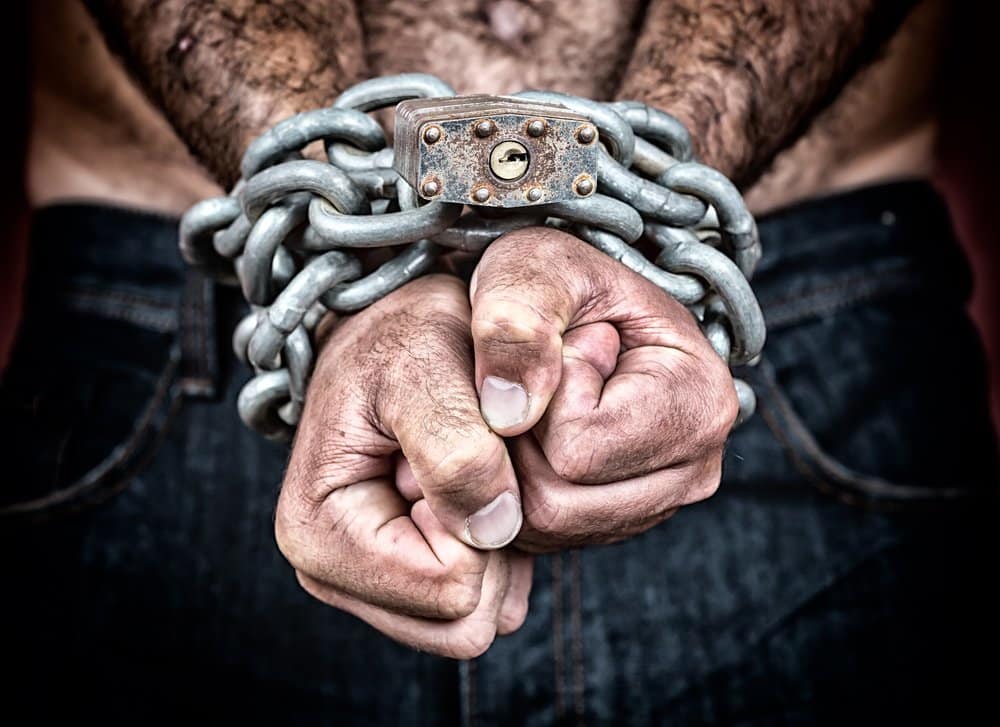 Detail of the chained hands of an adult man