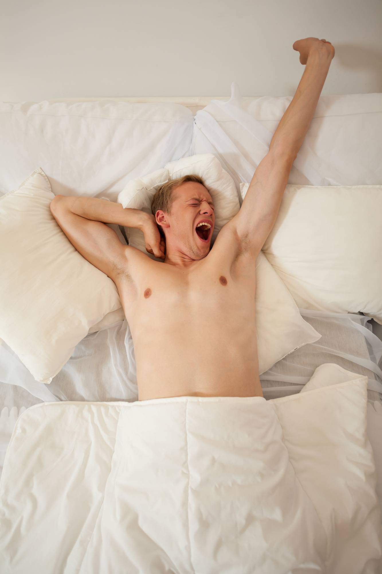 Man waking up and yawning in bed