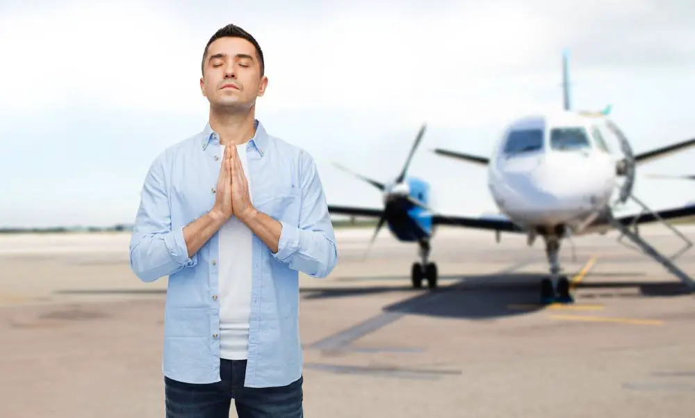 man praying over airplane on runway background