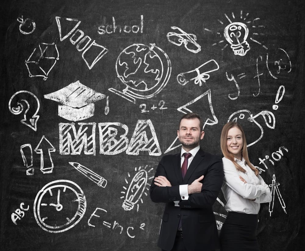 Young students are pondering over the business degree. A concept of the MBA degree. Drawn educational icons on the chalkboard.