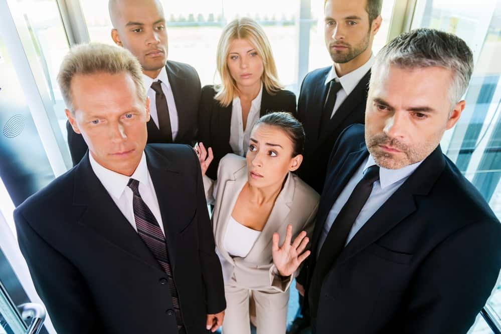 Drowning in people. Top view of fearful young woman in formalwear feeling trapped by the crowd while standing in elevator