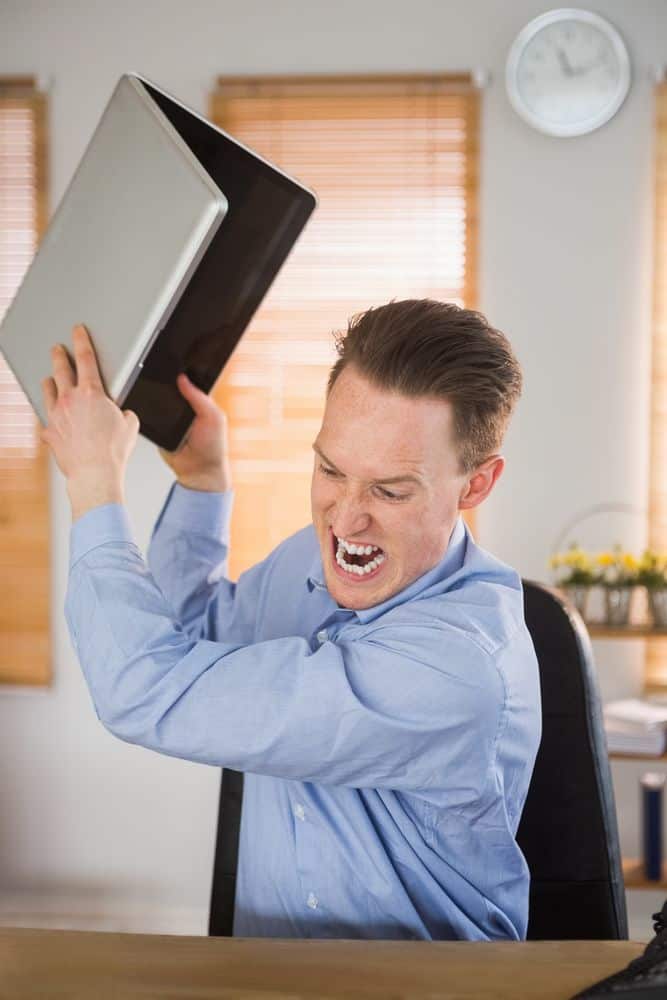 Furious businessman about to smash his laptop in the office