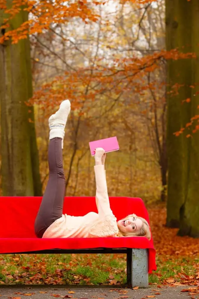girl relaxing in autumn park reading book